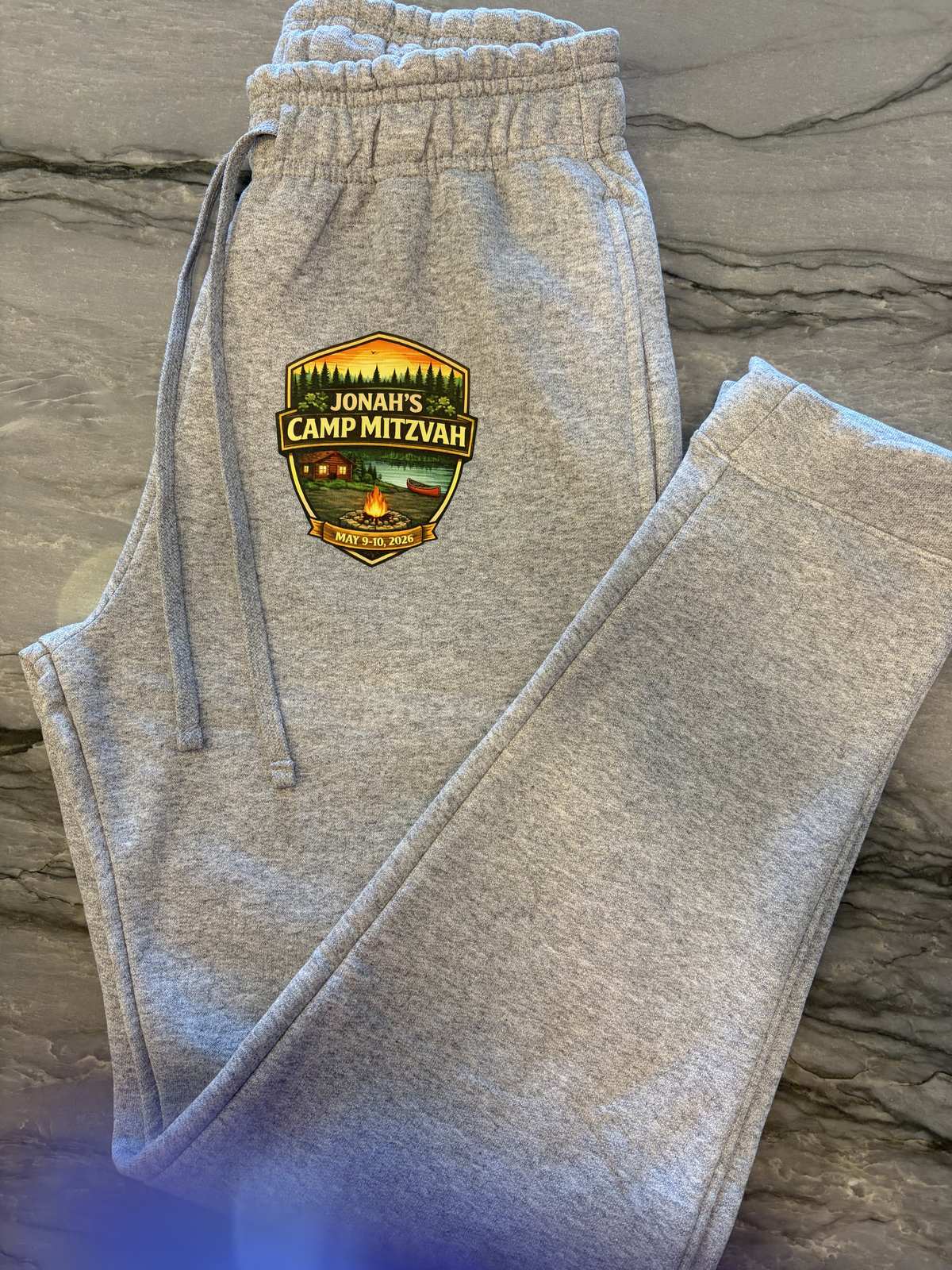 Grey custom sweatpants with an embroidered bar mitzvah camp logo patch