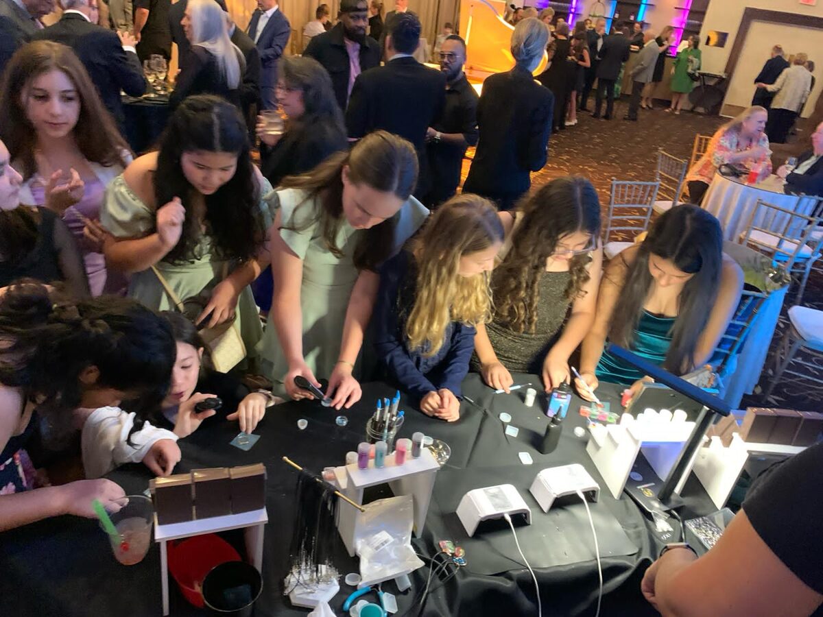 Crowd of teen guests gathered around a resin station at a mitzvah party