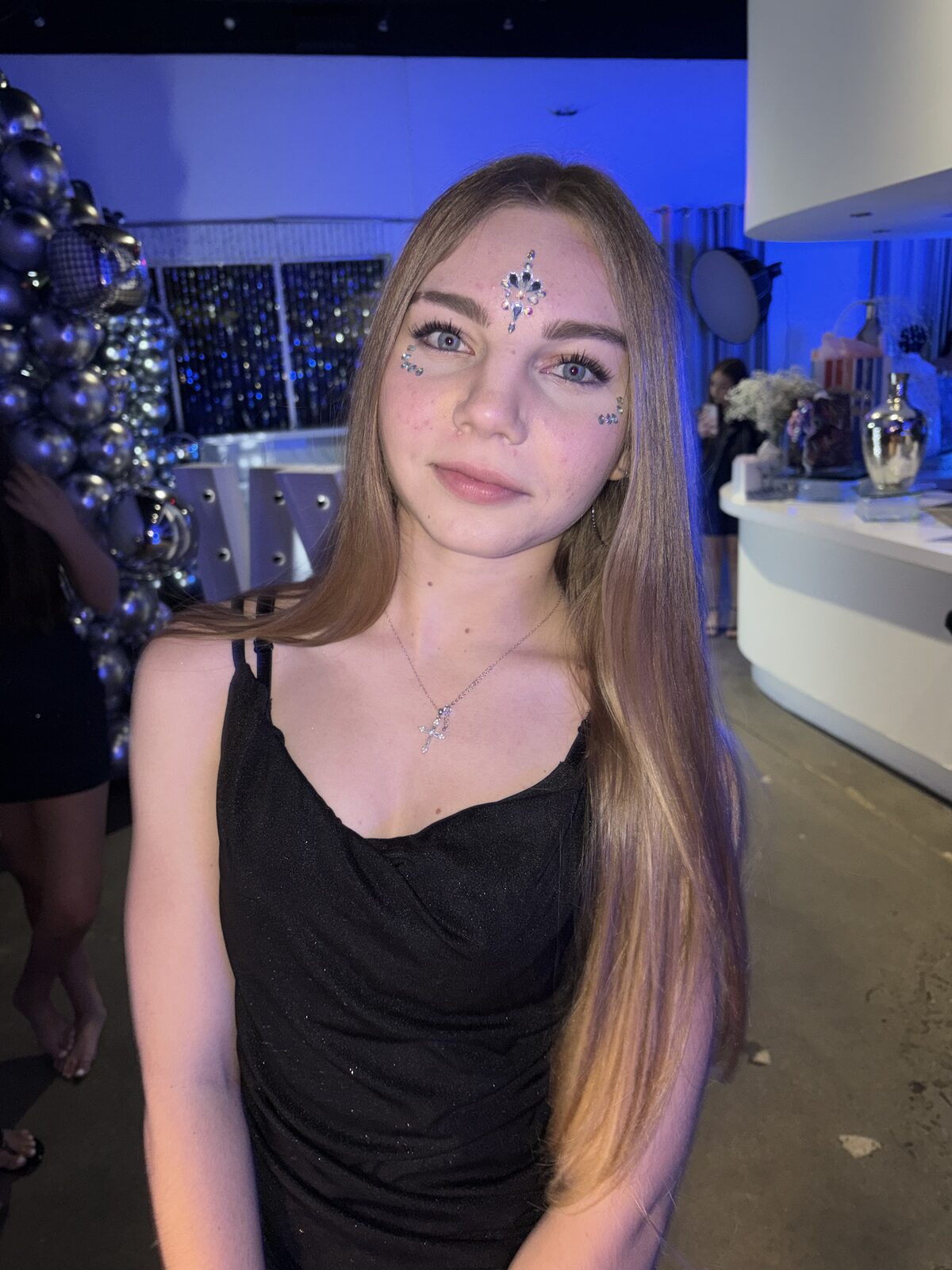 Teen guest wearing face gems at an evening mitzvah celebration