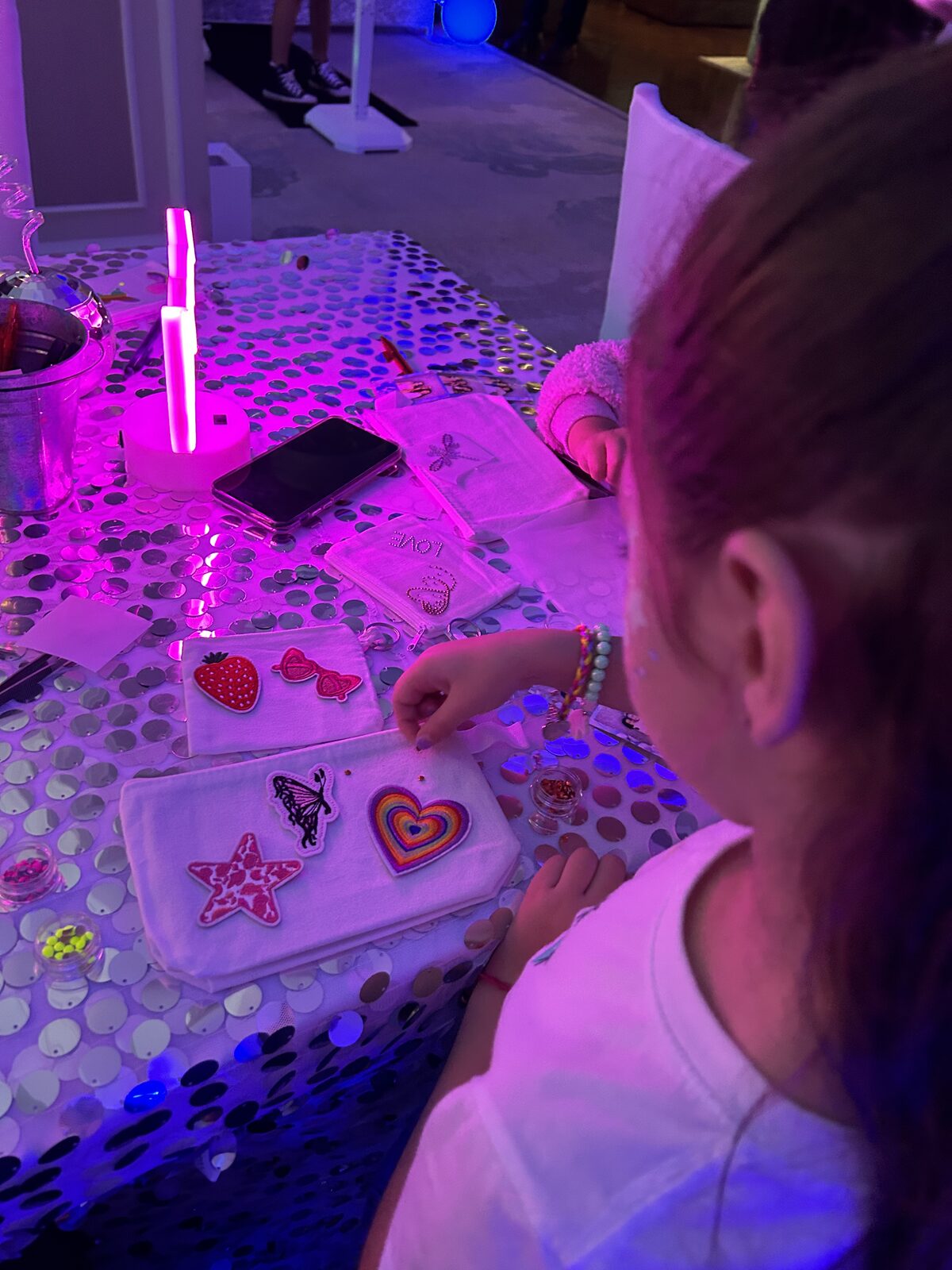 Guest making resin at a station under pink neon lighting at a party