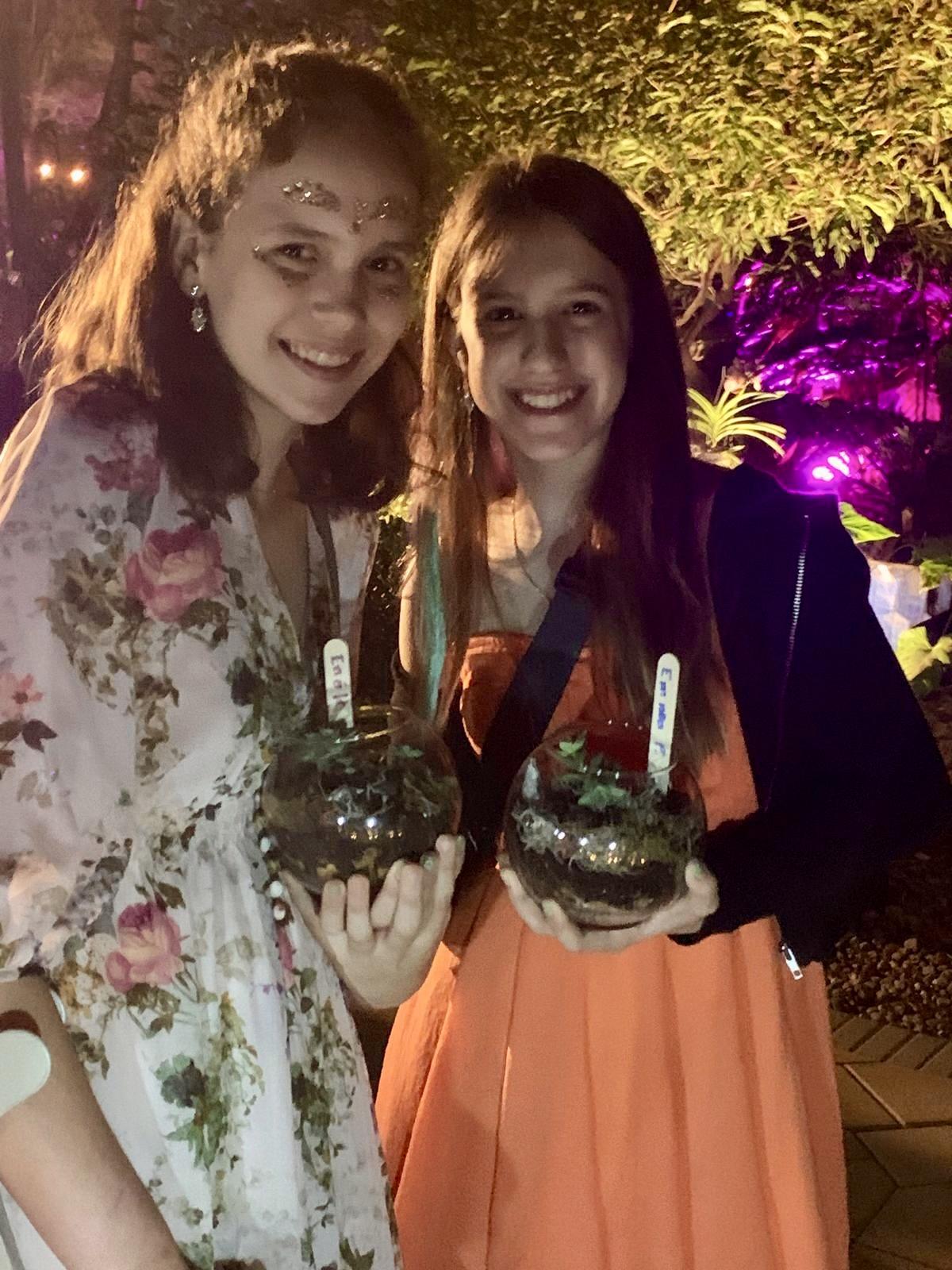 Two teen guests holding the terrariums they made at a party