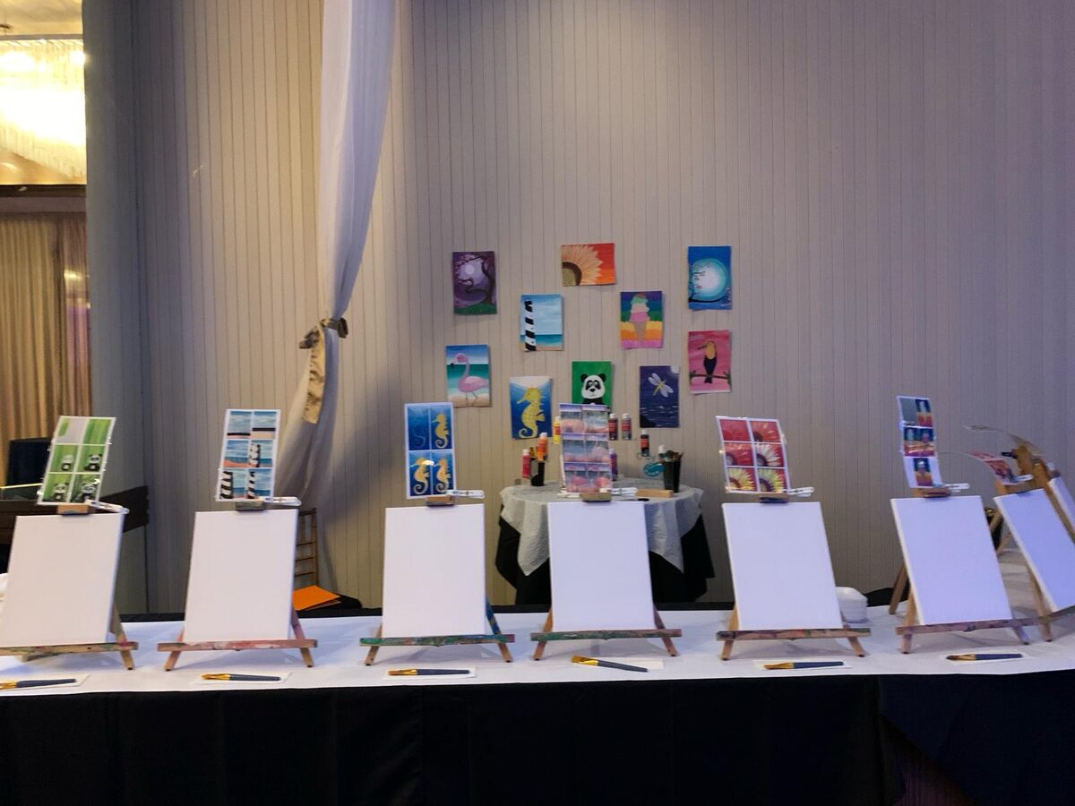 Canvas painting station with finished artwork displayed at a ballroom event