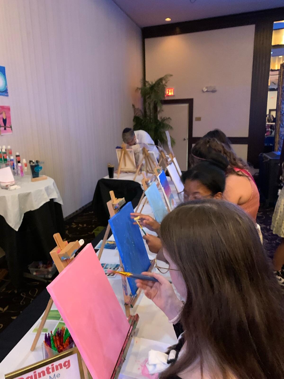 Guests painting canvases at easels during an event