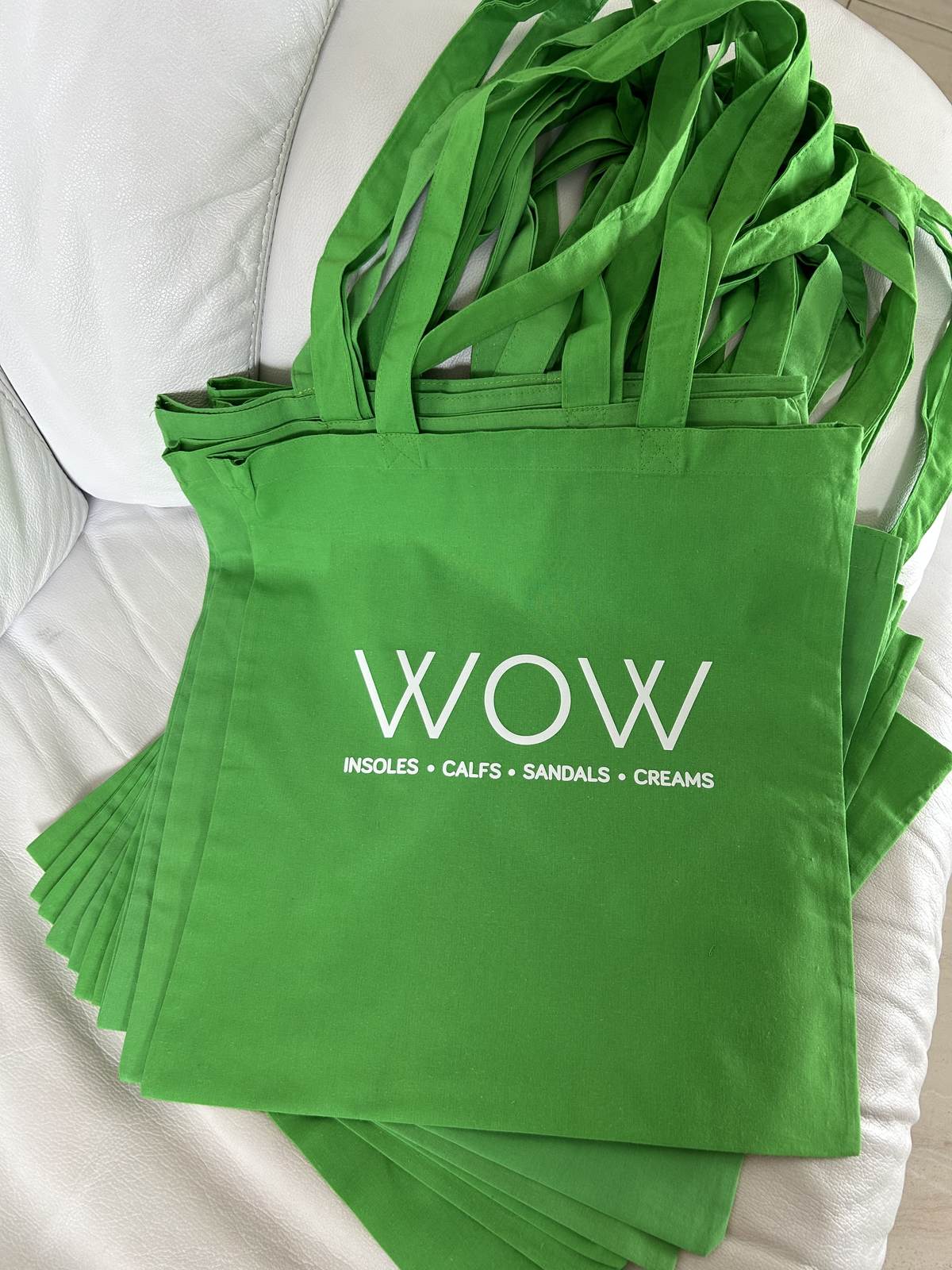 Stack of green custom promotional tote bags printed for a business