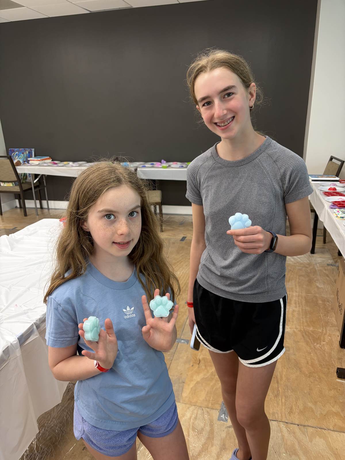 Two girls showing the resin pieces they made