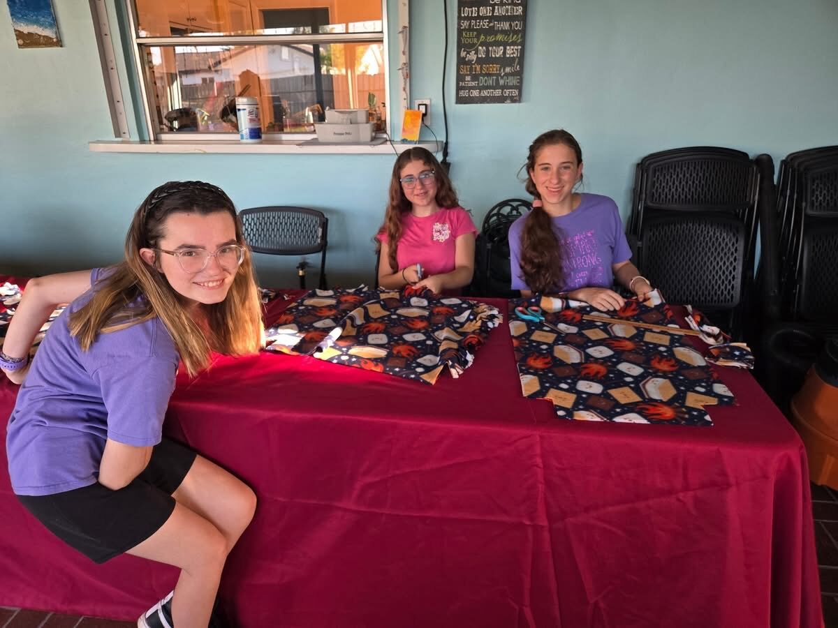 Teens working together on a fleece blanket tying service project
