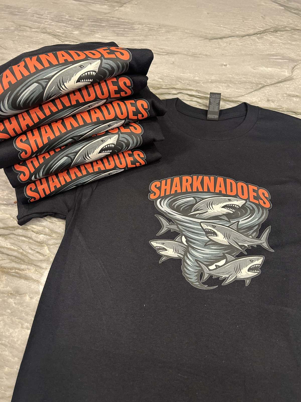 Stack of custom team t-shirts printed with a mascot design