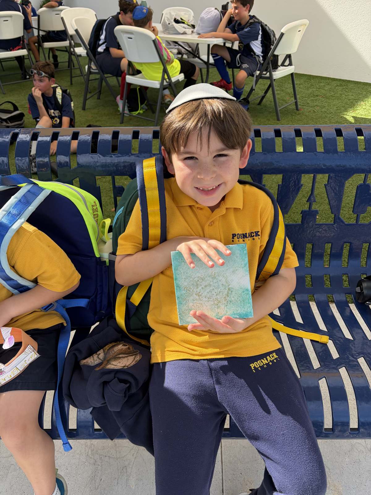 Student holding an art project he made at a school program