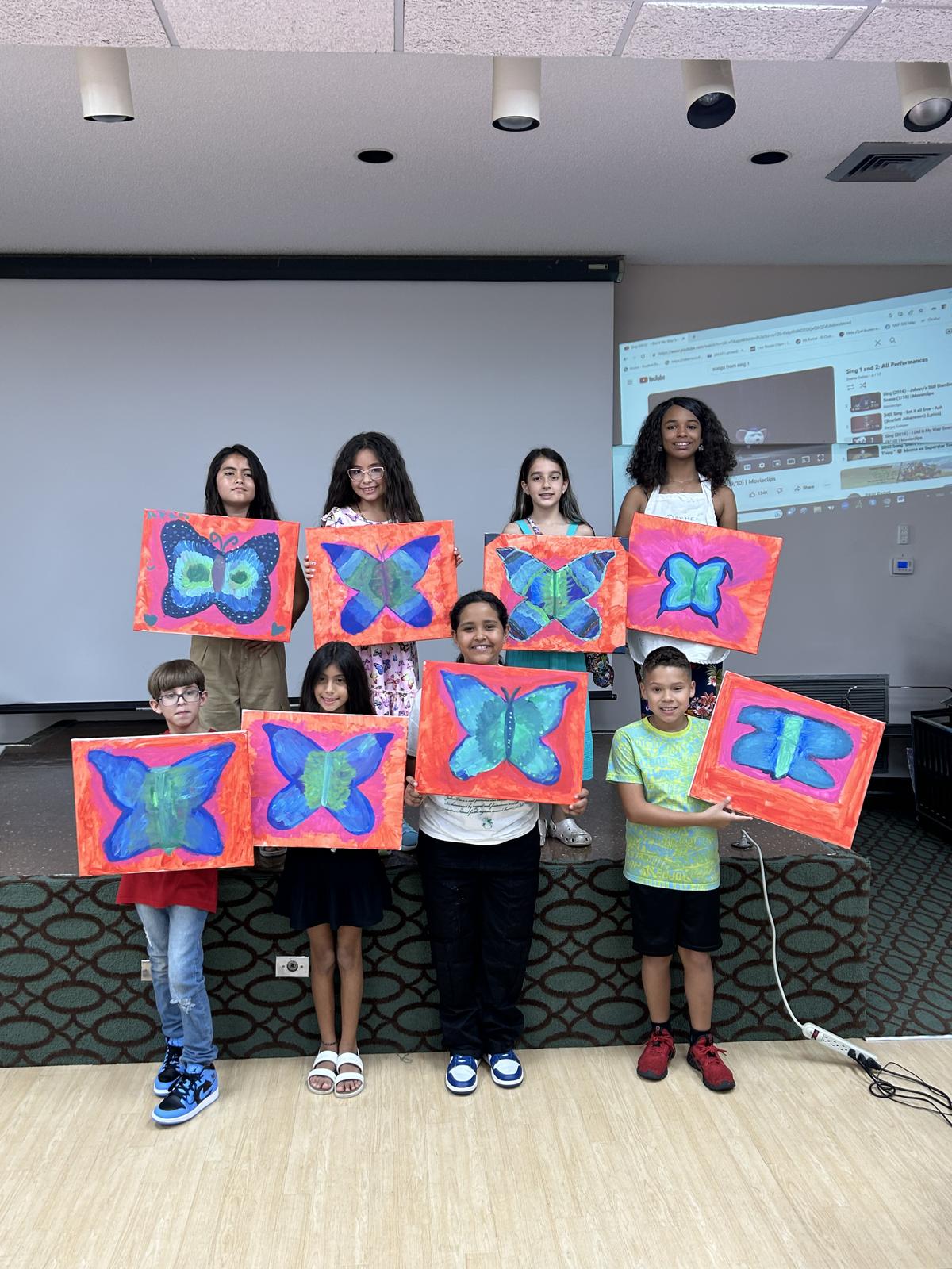 Group of students holding up the butterfly paintings they made