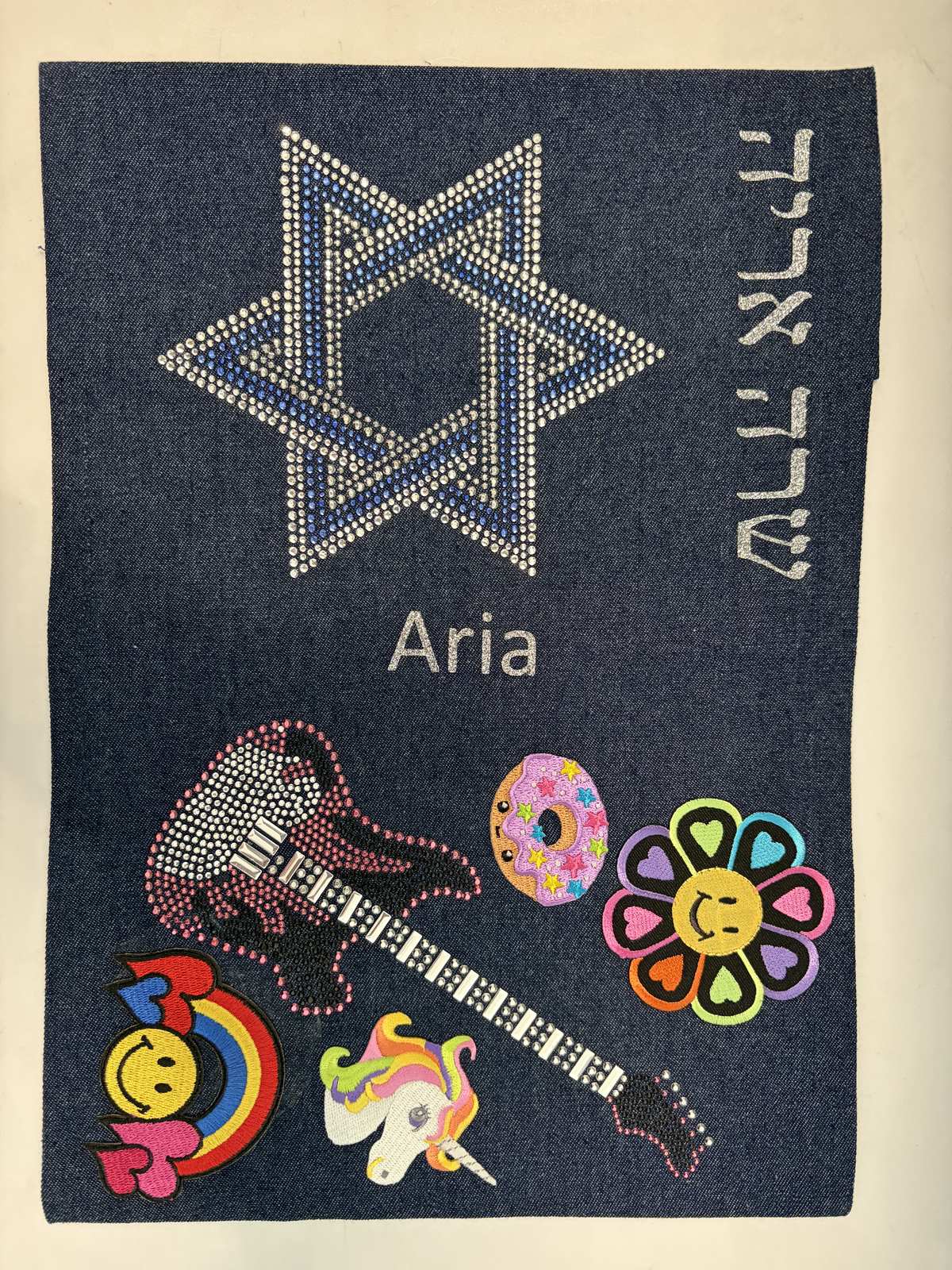 Denim siddur cover with a rhinestone Star of David, guitar and flower patches