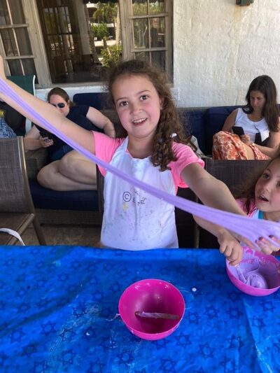 Girl stretching purple slime she made at an outdoor party