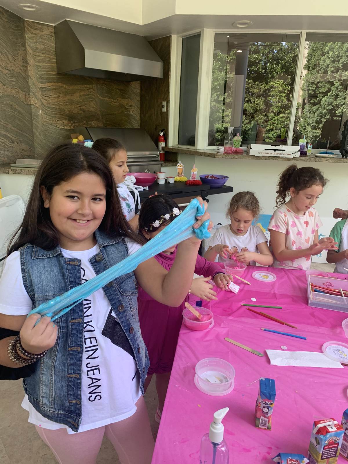 Girls at a pink craft table making and stretching slime