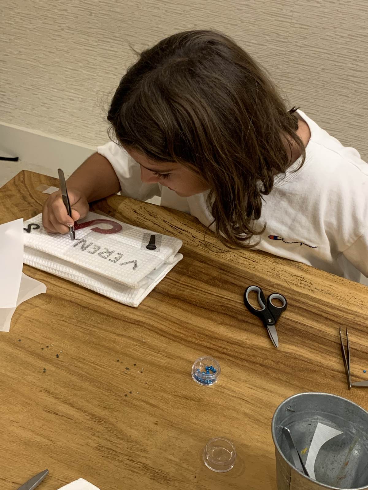 Child writing a name onto a wood plaque at a craft station