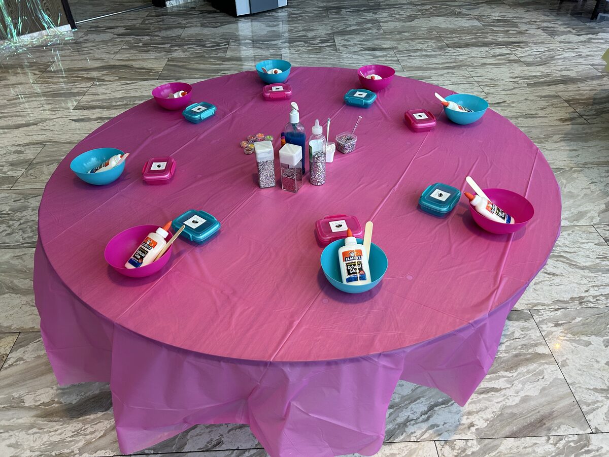 Round party table set with craft supplies on pink linens
