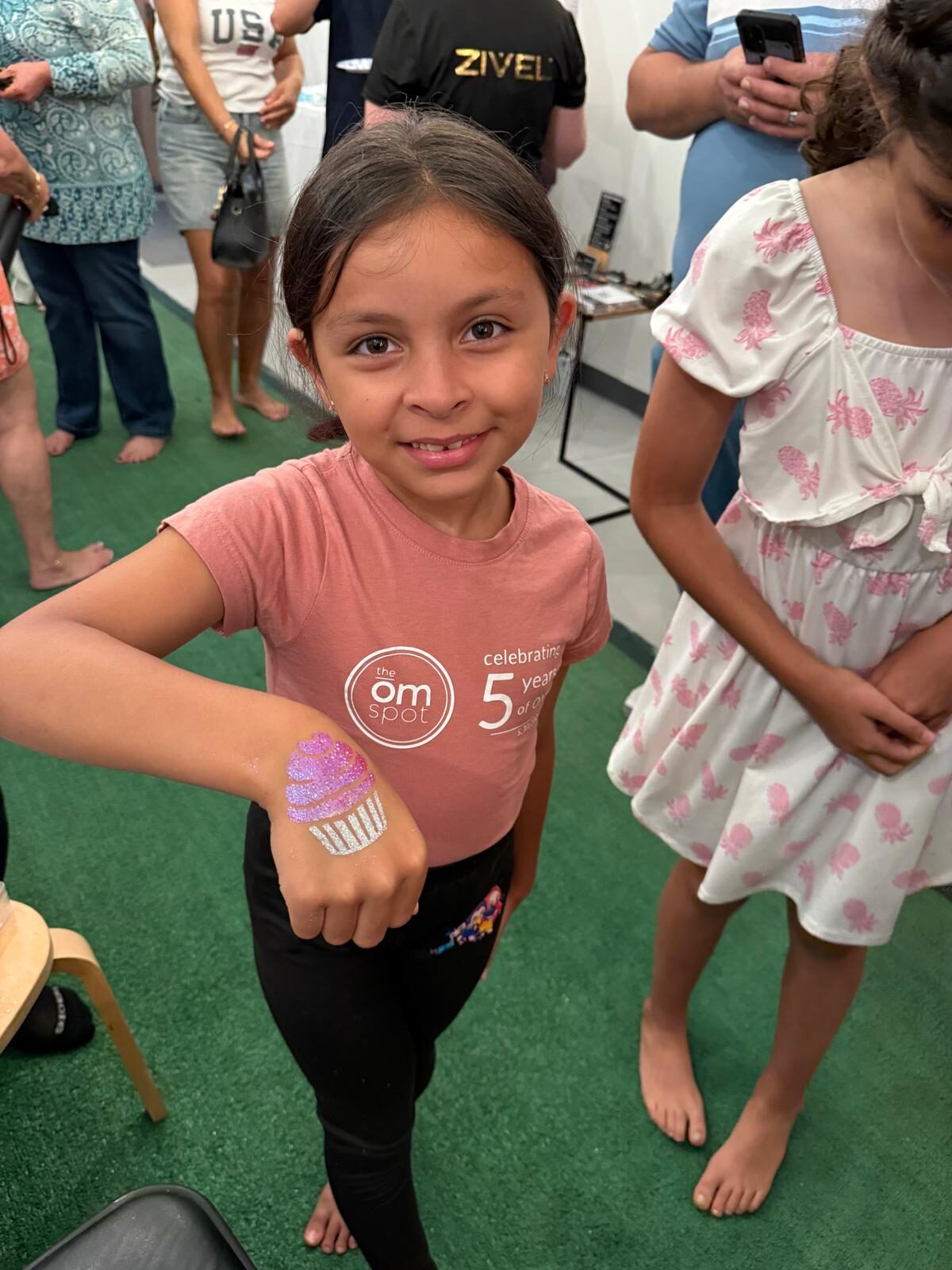 Girl with a cupcake glitter tattoo on her arm at an event