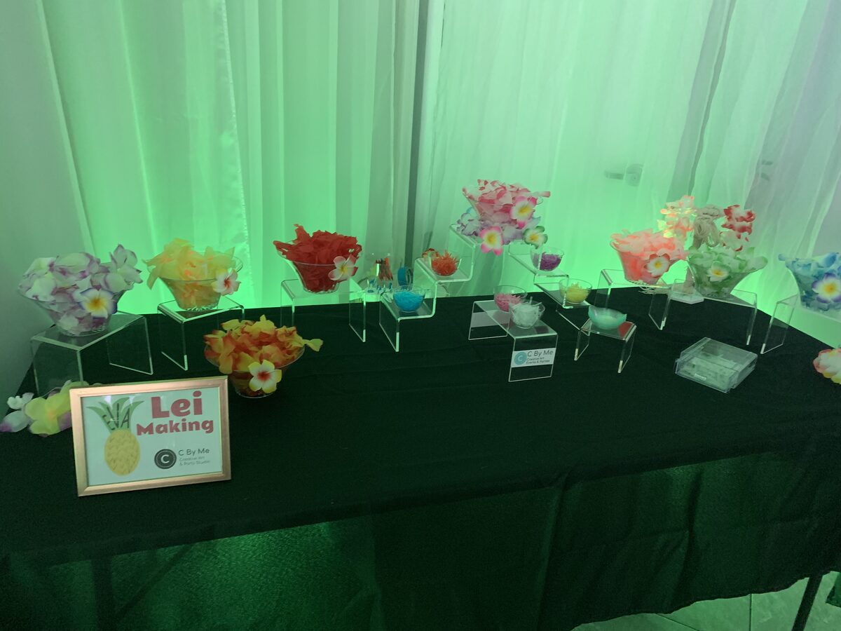 Lei making station set up with tropical flowers under green lighting