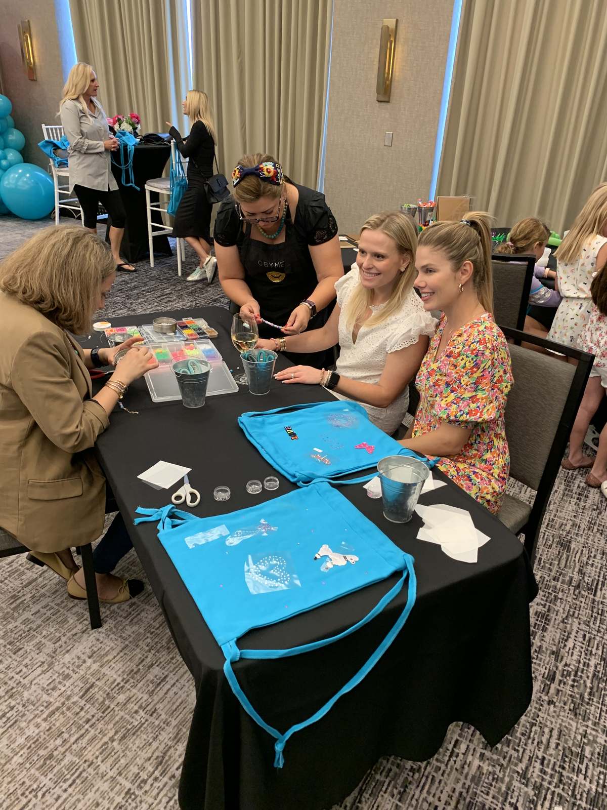 Guests decorating teal tote bags with patches at a craft station